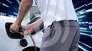 Progressive man charge electric car with technology background of binary code.