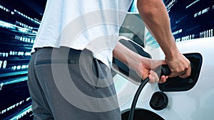 Progressive man charge electric car with technology background of binary code.
