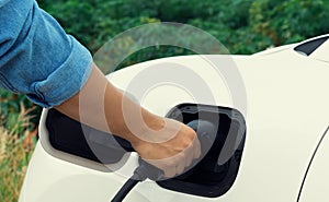 Progressive natural scenic of hand insert charging plug to EV car.