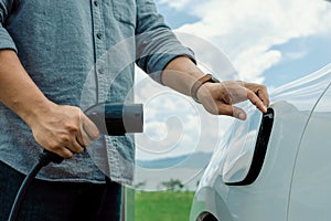 Progressive natural scenic of hand insert charging plug to EV car.