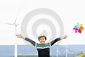 Progressive young asian boy playing with wind pinwheel toy at wind turbine farm.