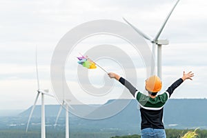 Progressive young asian boy playing with wind pinwheel toy at wind turbine farm.