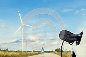 Progressive young asian boy playing with wind pinwheel toy at wind turbine farm.