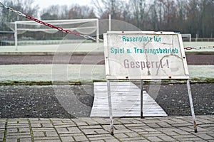 Prohibition sign `locked lawn for games and training` with the inscription in german language in front of a soccer field