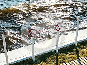 prohibitory signs on the pier do not fishing and diving to swimming. Lapping wave water