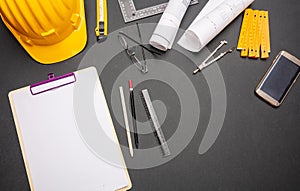 Project blueprints, yellow hardhat and engineering tools on black