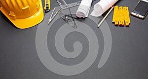 Project blueprints, yellow hardhat and engineering tools on black