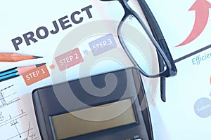 Project document with with calculator, pencil and eyeglasses.