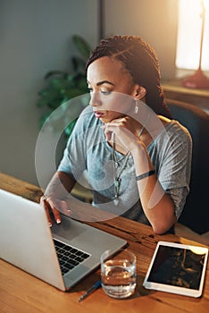 The project comes first. a young woman using her laptop while working late in her office.