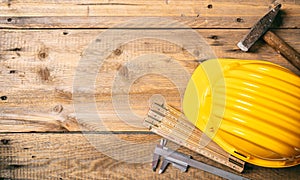 Project construction. Yellow hard hat and tools on wooden desk, copy space, top view