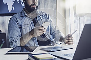 Project manager using digital devices and gadgets in work. Man checking email and sending messages on mobile phone