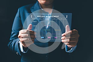 Project manager is working on virtual screen, using project management system. Gantt chart interface to plan tasks, schedule