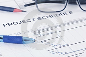 Project schedule document with pen, pencil, eyeglases and gantt chart