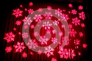 The projected pink icicle on the red curtain of a stage