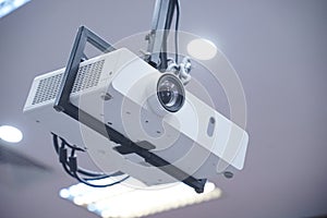 Projector hang on black ceiling in big meeting room or university. Closeup projector for cinema and presentation