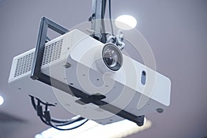 Projector hang on black ceiling in big meeting room or university. Closeup projector for cinema and presentation