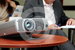 Projector on table with two person behind