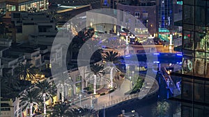 Promenade and canal in Dubai Marina with luxury skyscrapers and yachts around night timelapse, United Arab Emirates