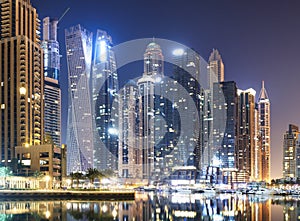 Promenade and canal in Dubai Marina at night with luxury skyscrapers around,United Arab Emirates