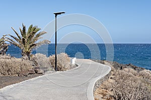 Promenade crossing through the volcanic rugged coastal terrain with scarce vegetation and linking several resorts