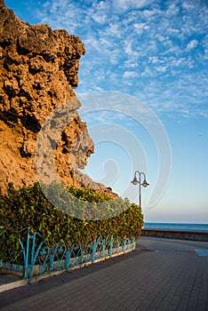 Promenade of Torremolinos, a road, rocks, blooming bushes and Mediterranean sea