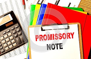 PROMISSORY NOTE text written on paper clipboard with chart and calculator photo