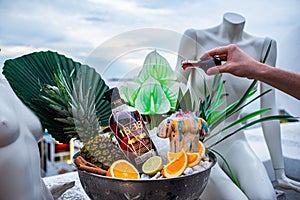 Promotional shot of rum bowl with ice pineapple orange hand of the bartender