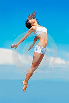 Propelled by an energy boost. A young woman in mid-air with her body outstretched.