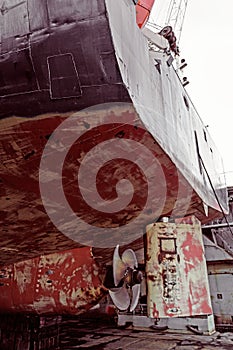 Propeller of cargo ship. Dry dock. View from stern. Rusty. Before repeating work