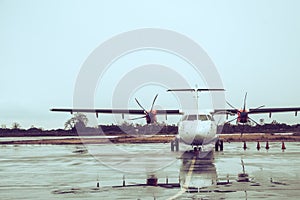 Propeller plane parking at the airport under rain.