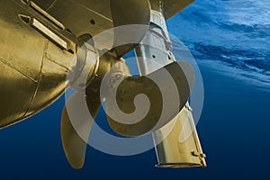 Propeller and rudder of big ship underway view from underwater. Close up image detail of ship