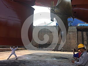 Propeller of the ship ,five blades, and rudder repairing, cleaning and painting during dry dock checked by workers and stevedores