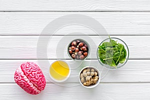 Proper nutrition for brain with nuts, spinage and oil stethoscope on white wooden background top view copy space