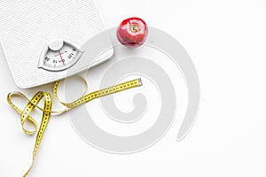 Proper nutrition for lose weight. Scale, measuring tape, apple on white background top view space for text