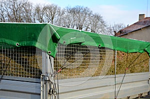 A properly covered pile of cut grass from garden maintenance on a trailer with a lattice superstructure for a larger capacity of t photo