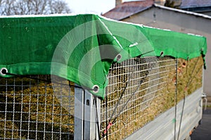 A properly covered pile of cut grass from garden maintenance on a trailer with a lattice superstructure for a larger capacity of t photo