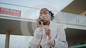 Property agent talking phone at house for sale. Serious african american discuss