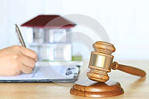 Property auction, Gavel wooden and model house with woman signing documents on the table, lawyer of home real estate and ownership