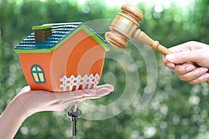 Property auction, Woman hand holding gavel wooden and model house on wtite background, lawyer of home real estate and ownership