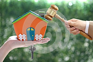 Property auction, Woman hand holding gavel wooden and model house on wtite background, lawyer of home real estate and ownership