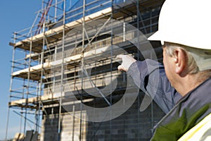 Property developer / builder pointing at building with scaffolding.
