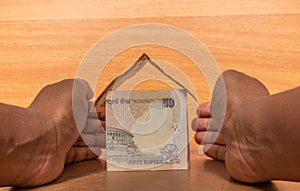 Property insurance concept, Hands protecting the house made with Indian paper currency