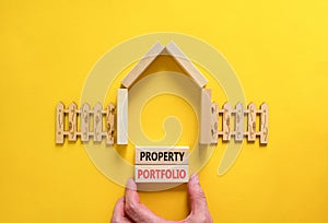 Property portfolio symbol. Concept words Property portfolio on beautiful wooden blocks. Model of house. Businessman hand.