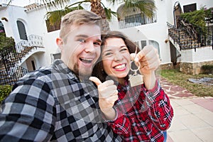 Property, real estate and rent concept - Happy funny young couple showing a keys of their new house