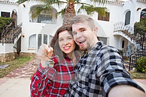 Property, real estate and rent concept - Happy funny young couple showing a keys of their new house