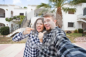 Property, real estate and rent concept - Happy smiling young couple showing a keys of their new house