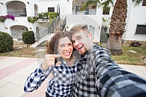 Property, real estate and rent concept - Happy smiling young couple showing a keys of their new house