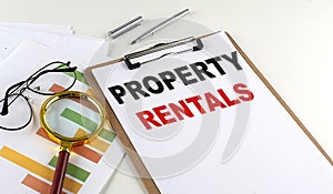 PROPERTY RENTALS text on clipboard with chart on white background, business concept