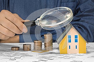 Property Tax on buildings - Property Real Estate concept with a small home model, euro coins group and magnifying glass