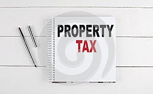 PROPERTY TAX text written on notebook on the wooden background